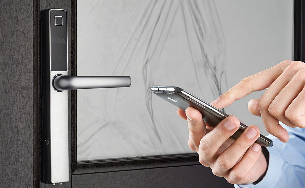 ERA Protect Smart 'Universal Door Handle. In Chrome. Stood next to  the handle are a pair of hands , with blue cuffs, holding and pointing to a smartphone. 