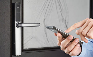 ERA Protect Smart 'Universal Door Handle. In Chrome. Stood next to  the handle are a pair of hands , with blue cuffs, holding and pointing to a smartphone. 